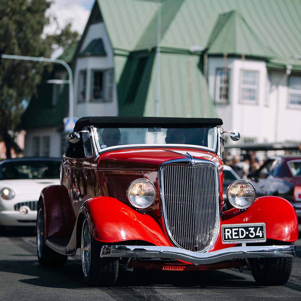 Red hot rod car on the road.
