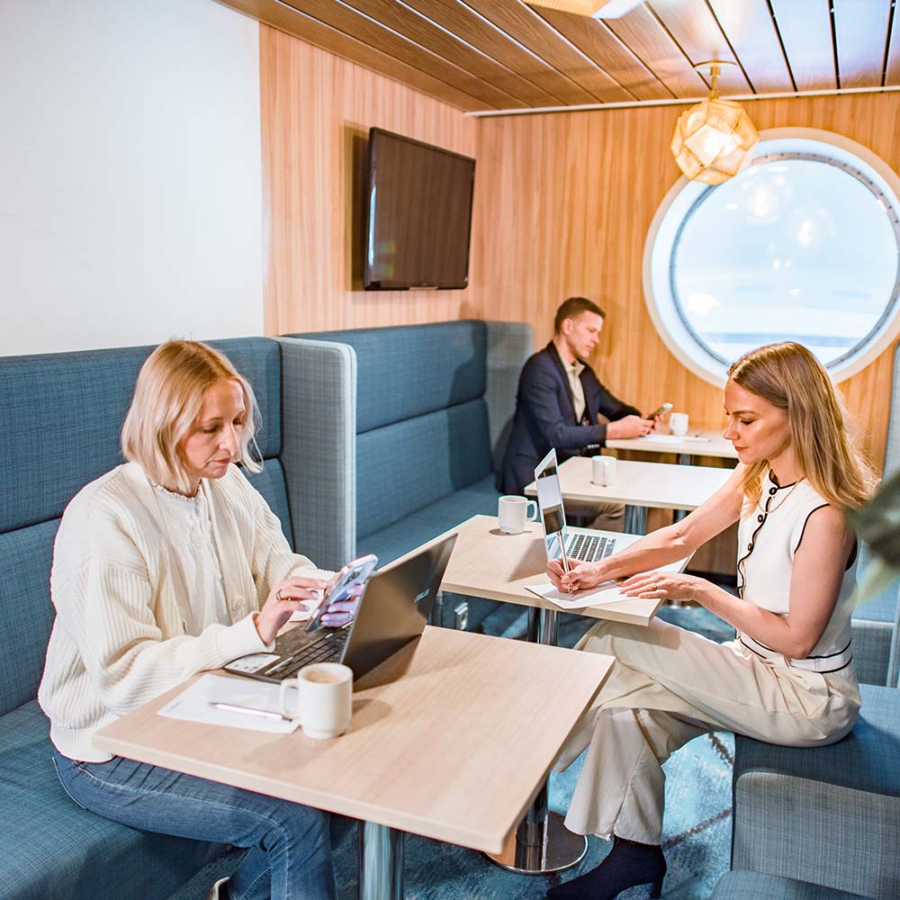 Three people working on laptops in the M/S Finlandia Lounge.