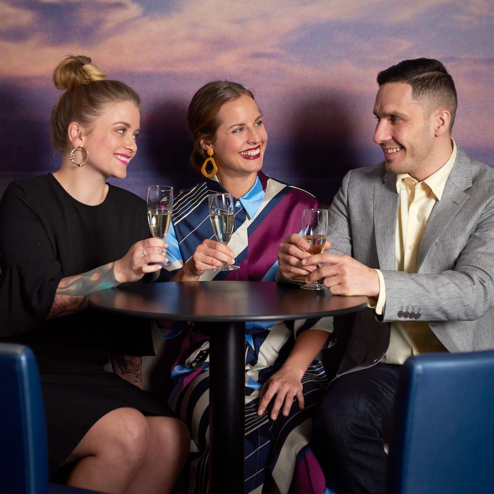 Smartly dressed two women and a man toasting.